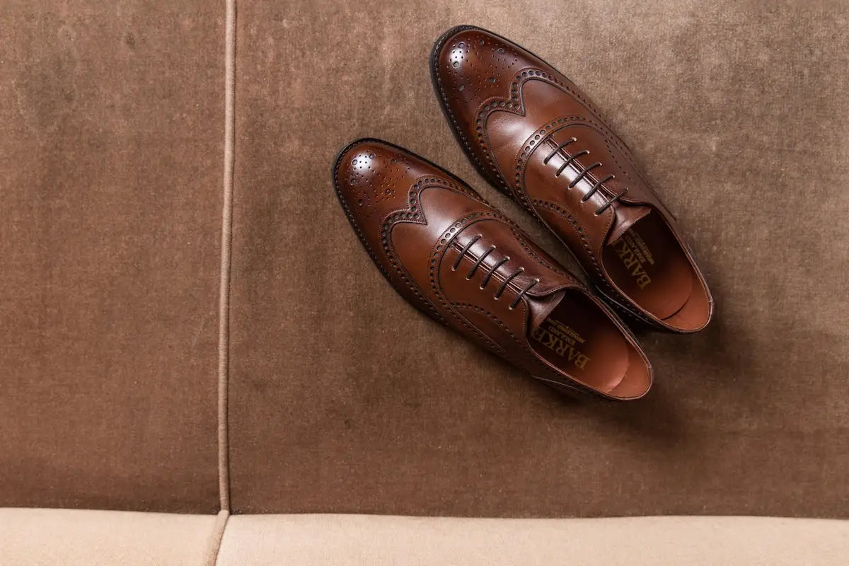 Brown leather brogue shoes with tan accents and intricate stitching.