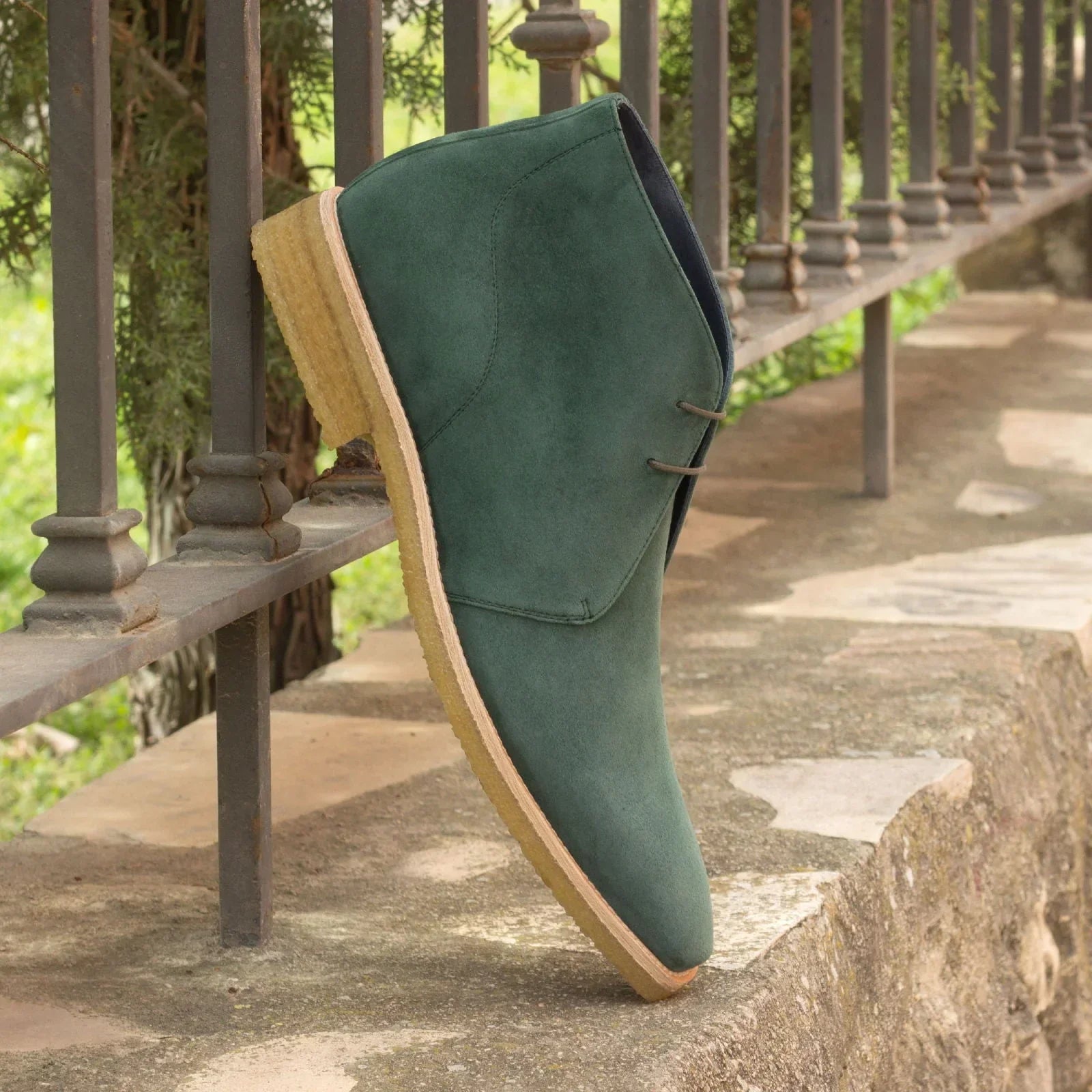 Green suede chukka boot with wooden sole and button detail.