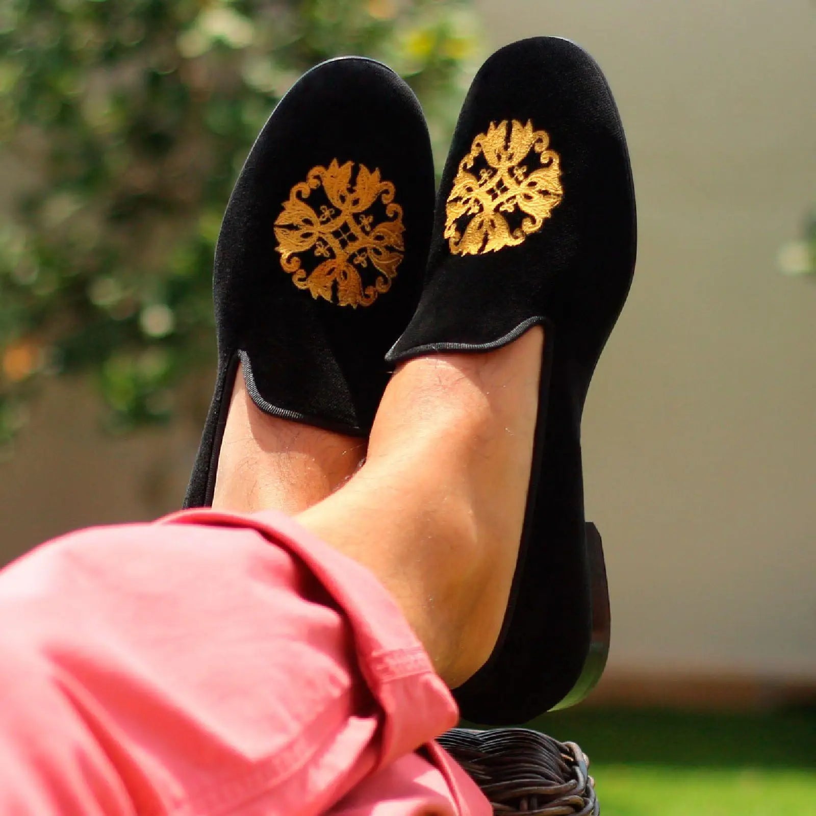 Black velvet loafers with gold embroidery.