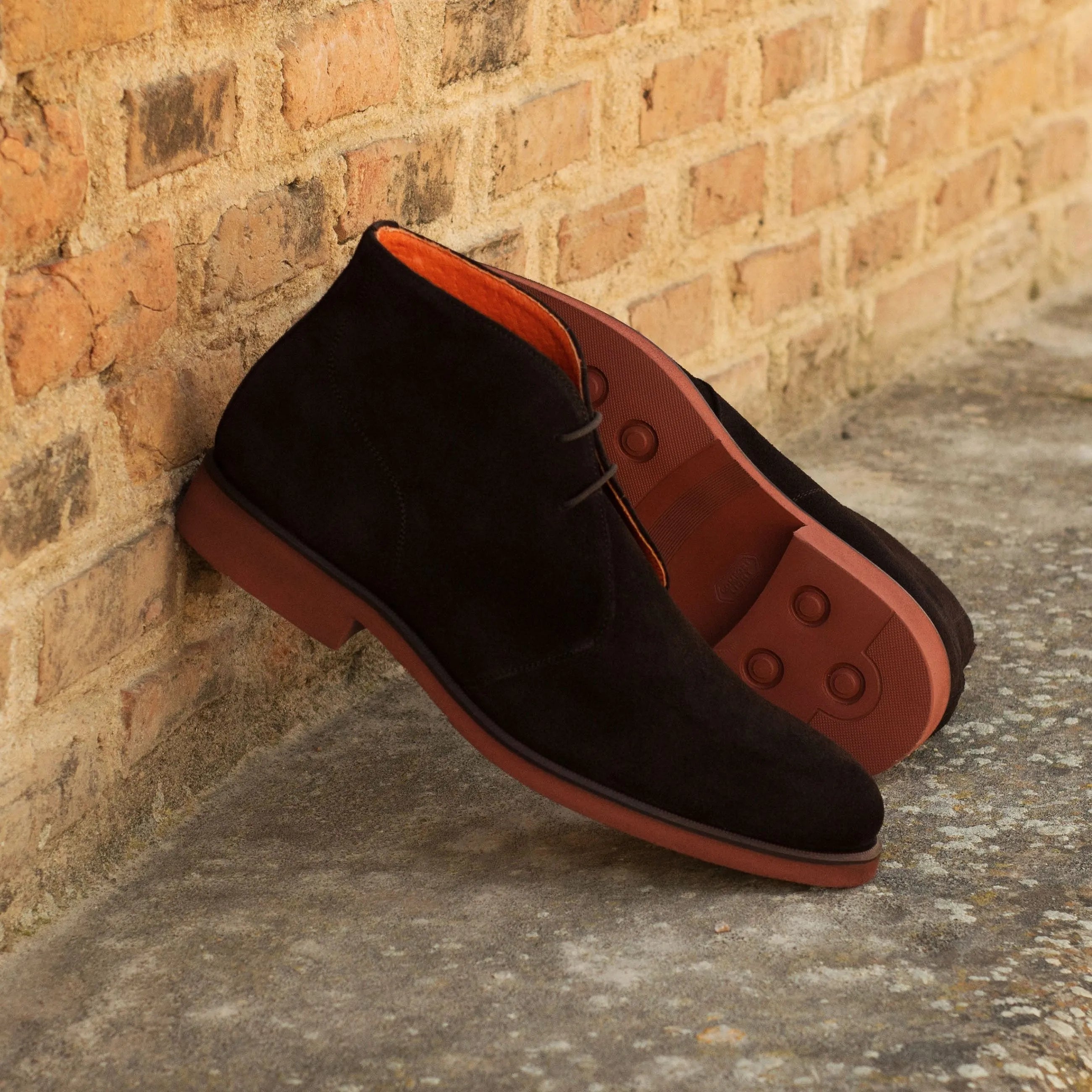 Black suede Demothi chukka boots featuring striking red soles for stylish footwear