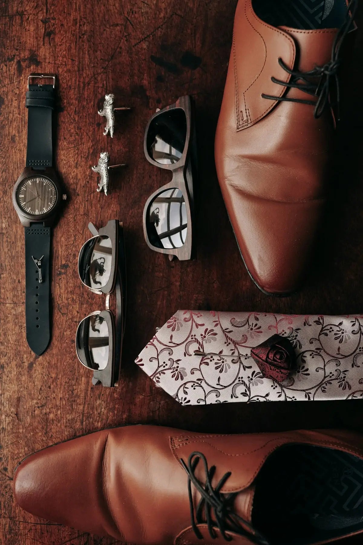 A pair of shoes, a tie, watch, and a watch on a table