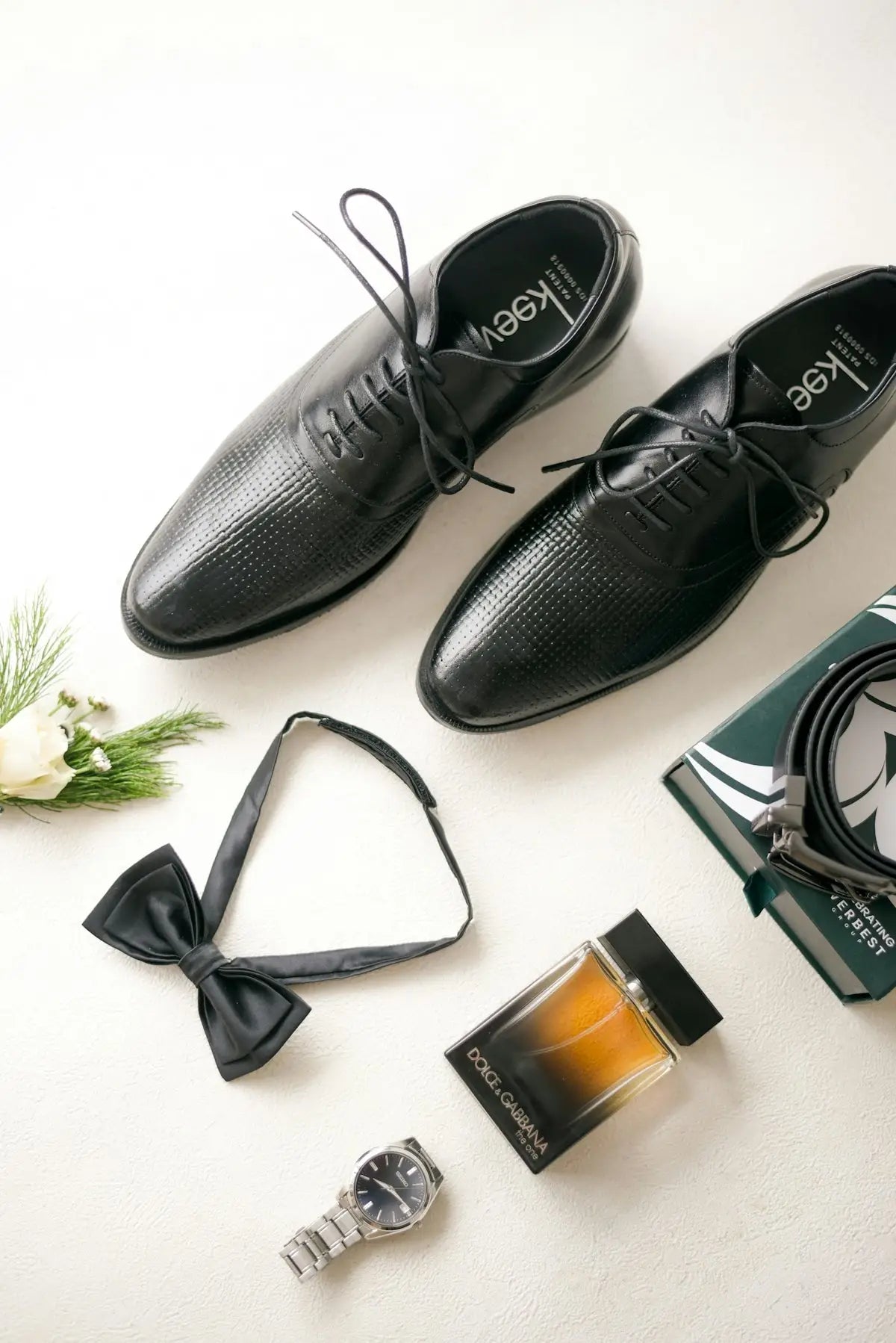 Groom's accessories: shoes, bow tie, watch, and cologne.