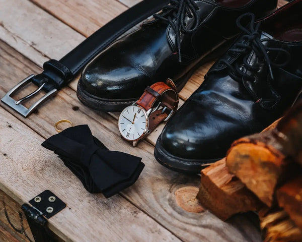 Men's formal accessories are arranged on wood.
