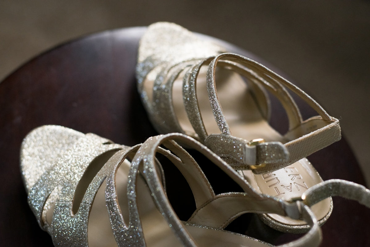 a pair of silver shoes sitting on top of a wooden table