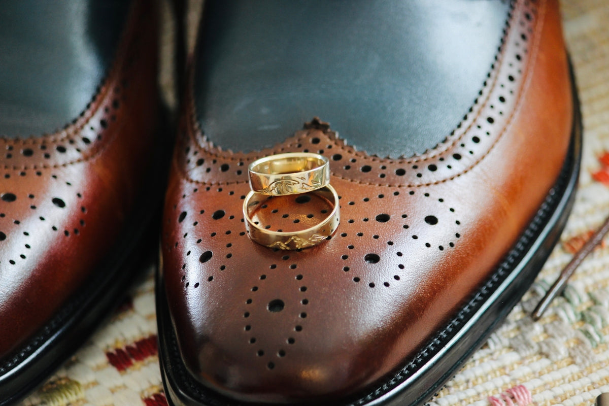A pair of brown shoes with a gold ring on them