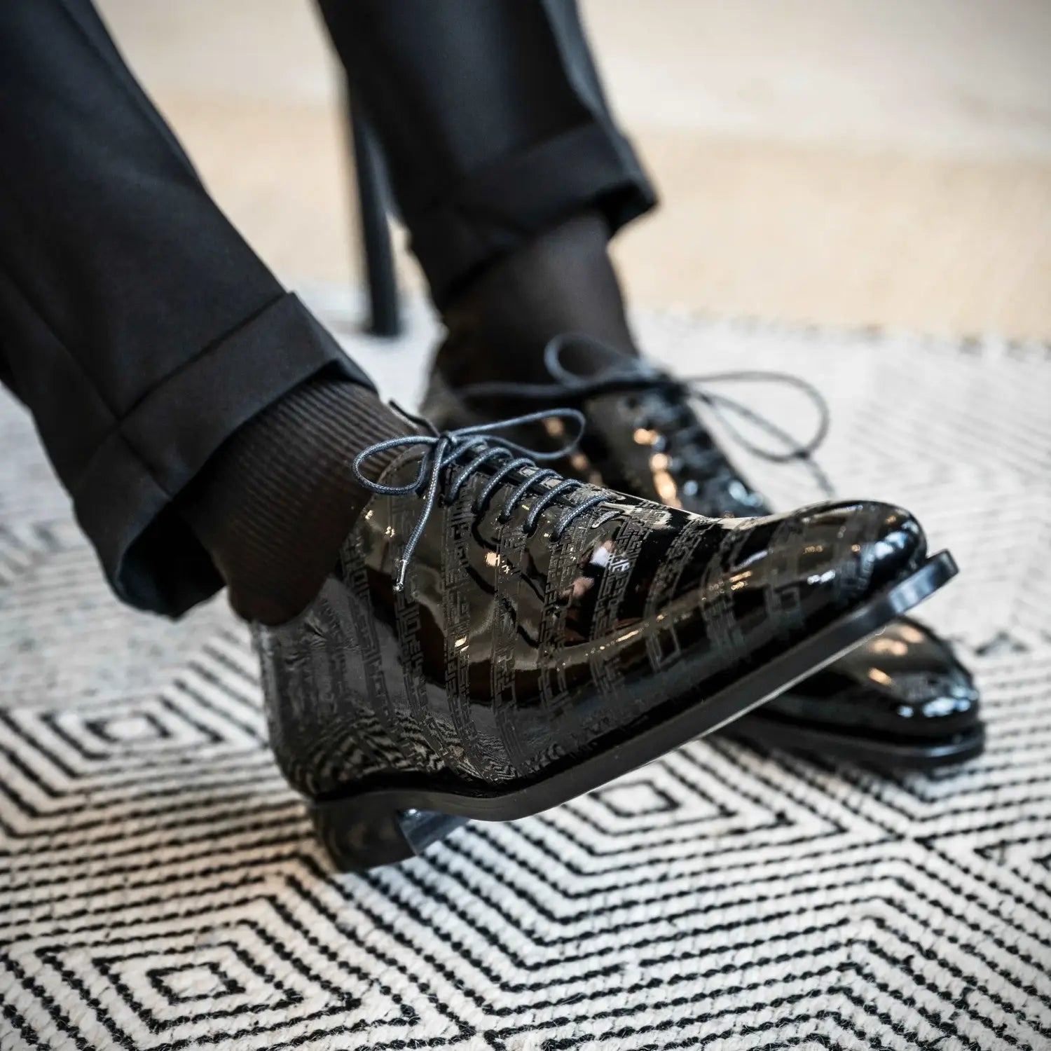 Black patent leather dress shoes with pointed toes and laces, classic design.