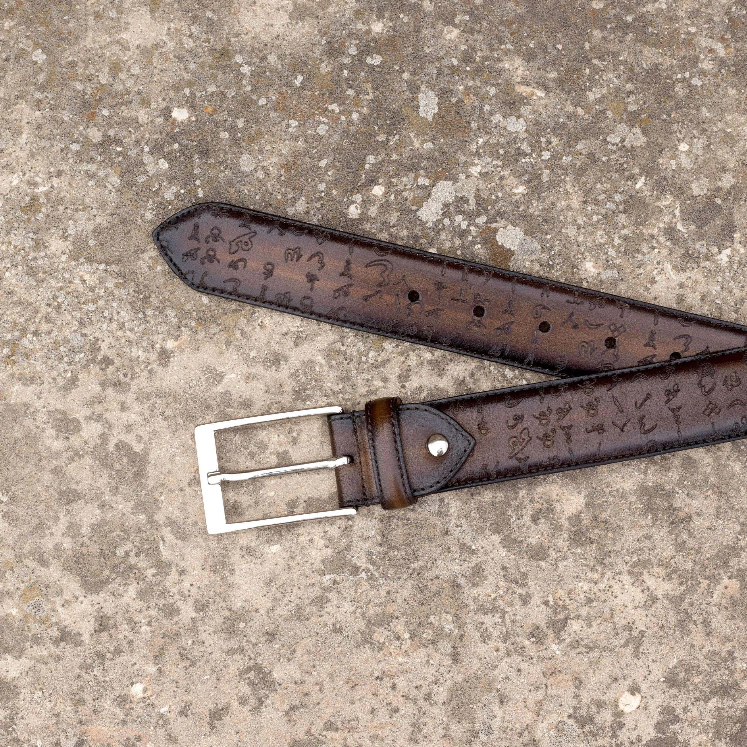 Brown leather belt with silver buckle, featuring Arabic Matrix Patina design