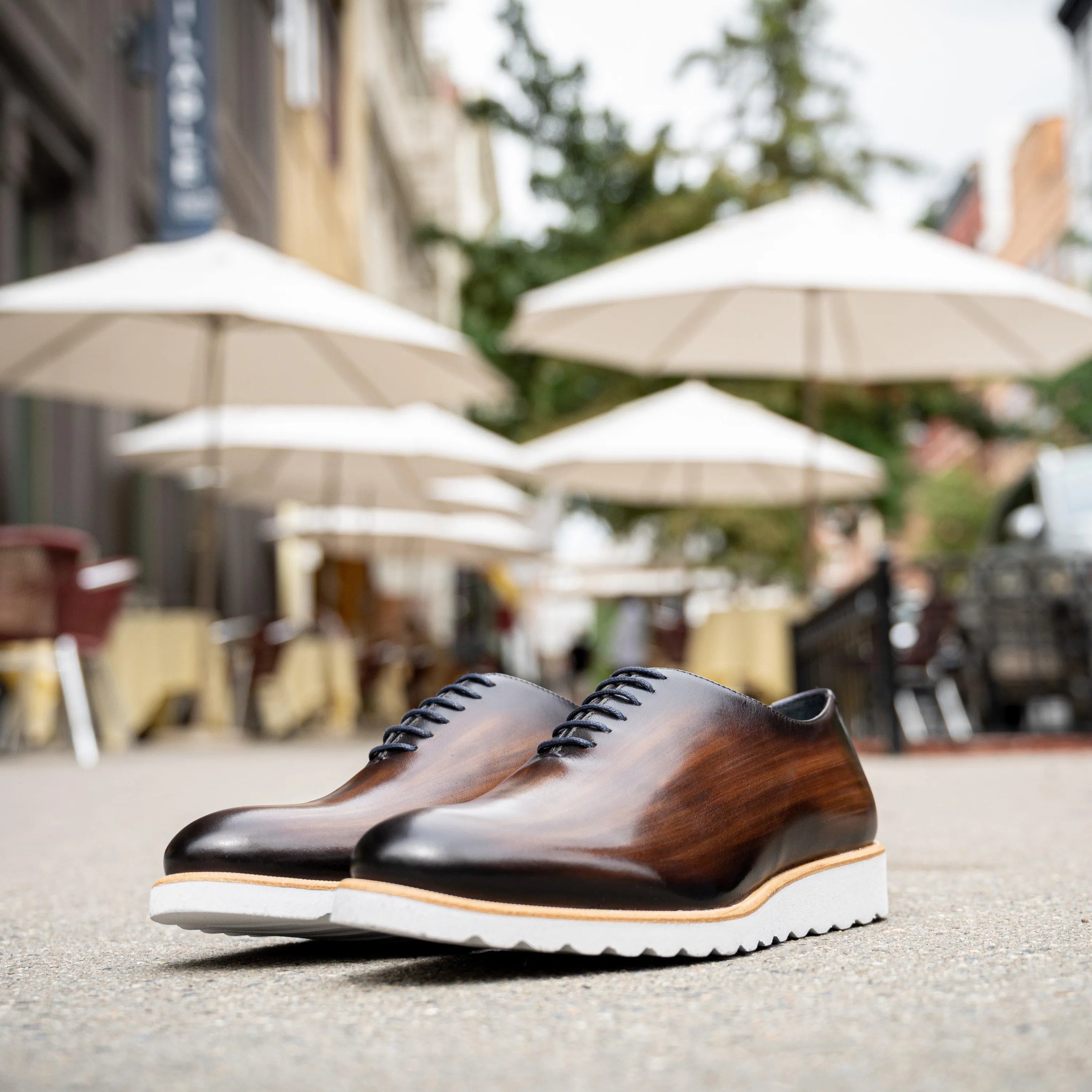 Brown leather dress shoes with white soles, showcasing the Dino Patina Wholecut design