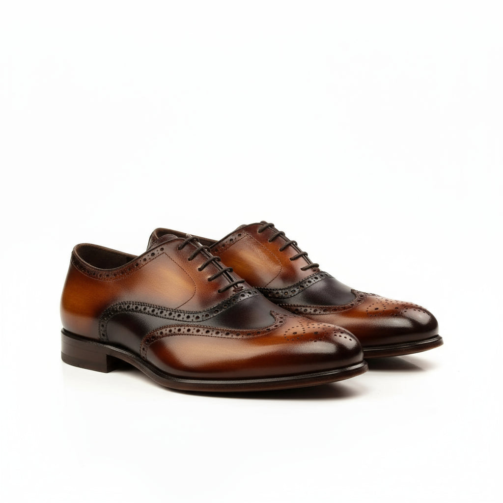 Two-toned brown leather wingtip dress shoes featuring a brogue patina design