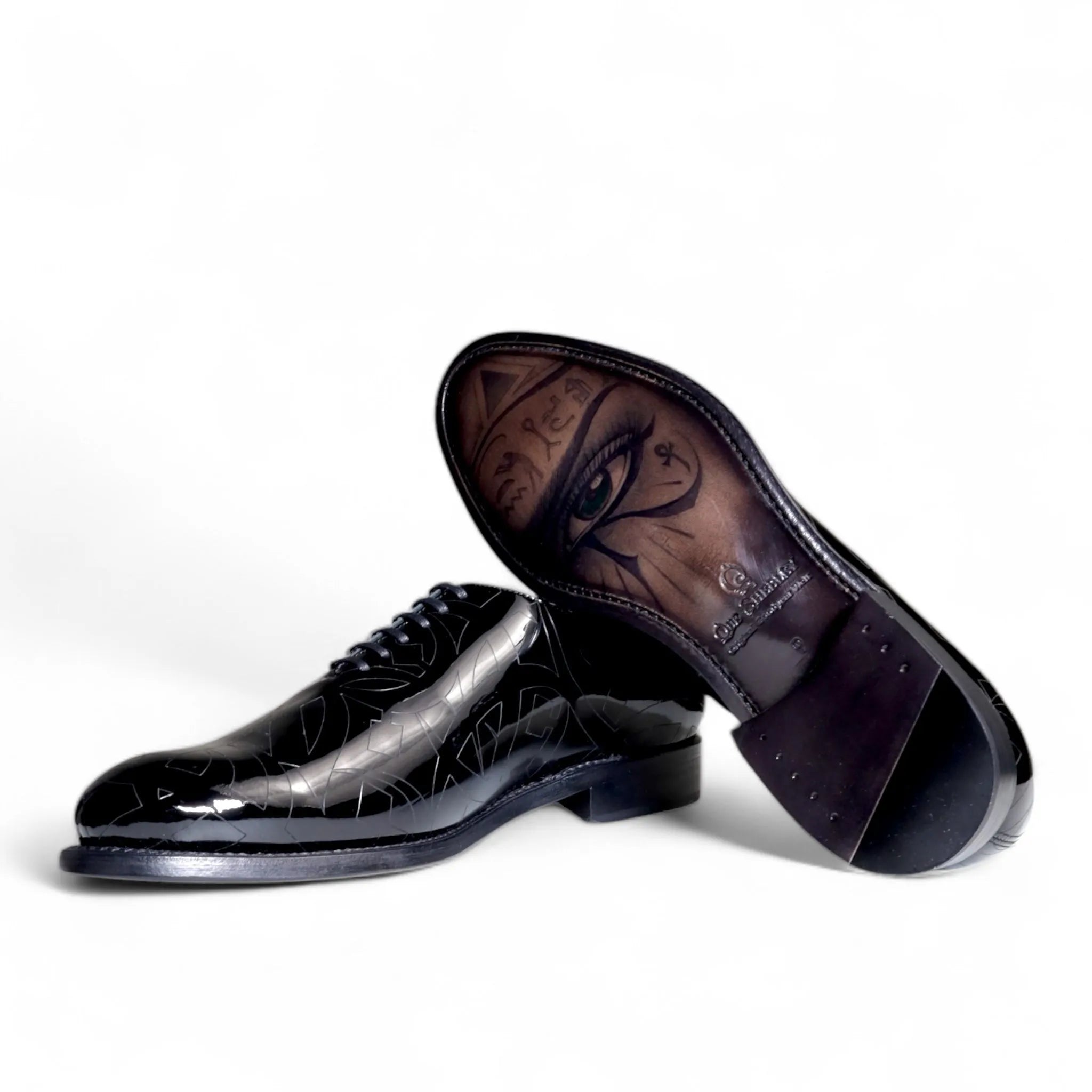 Shiny black Quswa Noir Wholecut Shoes featuring eye design on the sole
