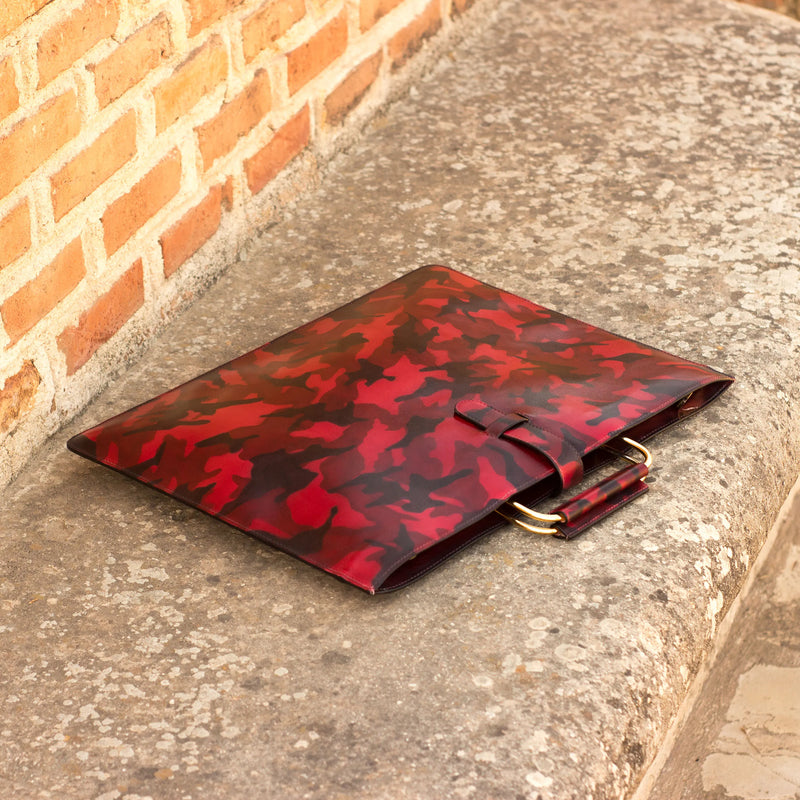 Red and black leaf-patterned clutch with gold handles from the Sunil Satchel Patina collection